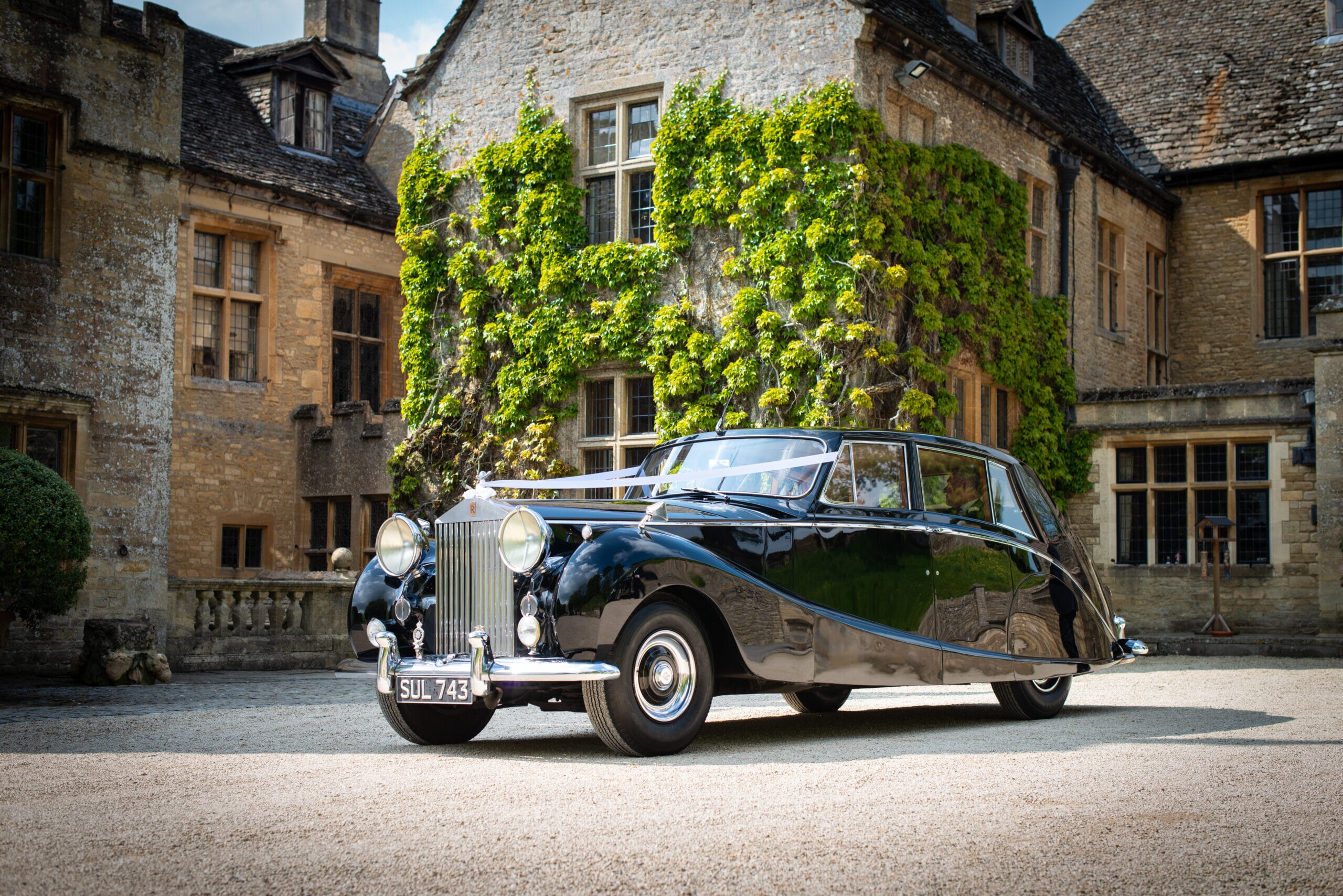 Rolls Royce wedding car parked in front of a stately home in the Cotswolds