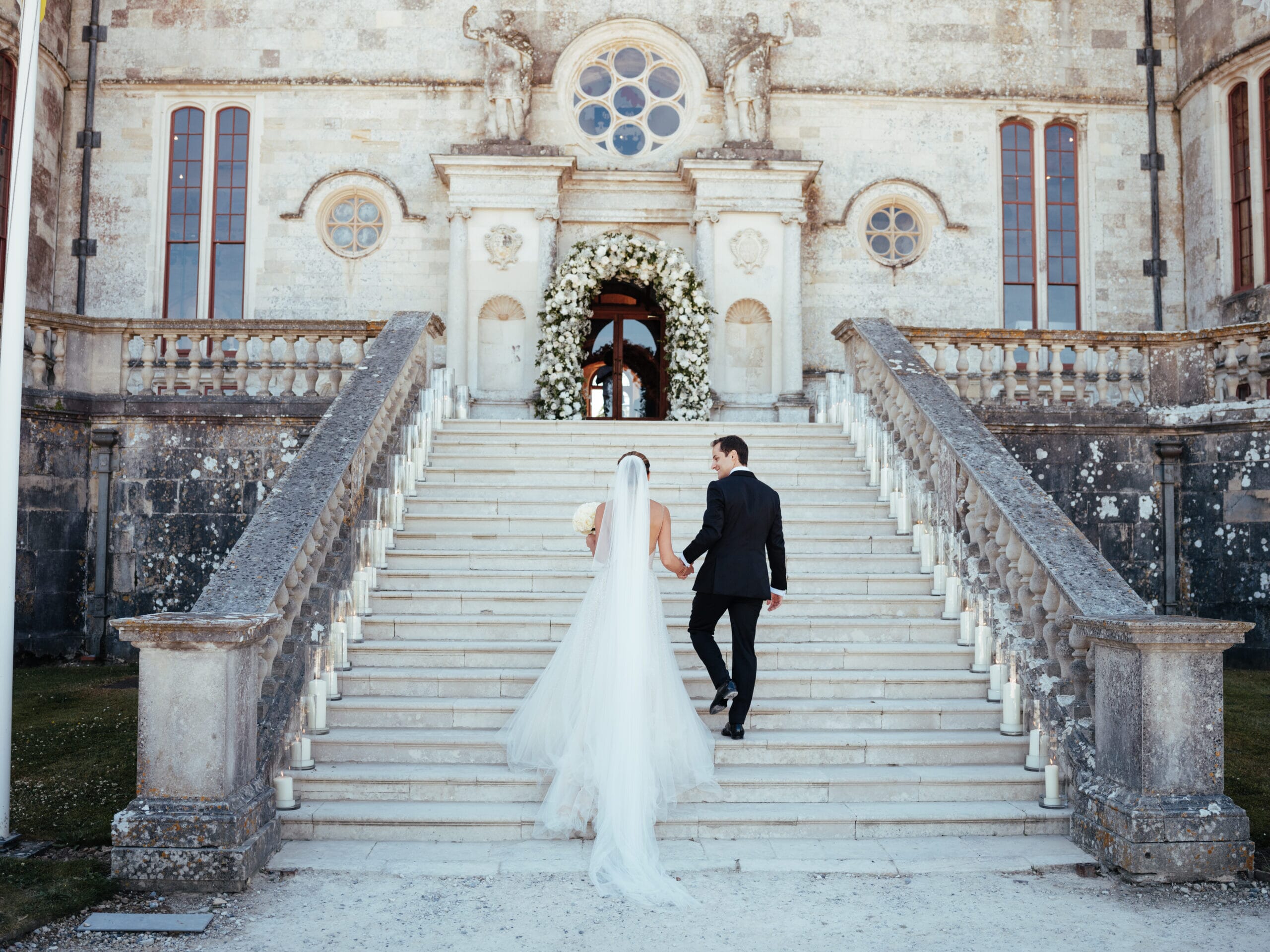 Bride and groom walking up the steps at Lulworth Castle